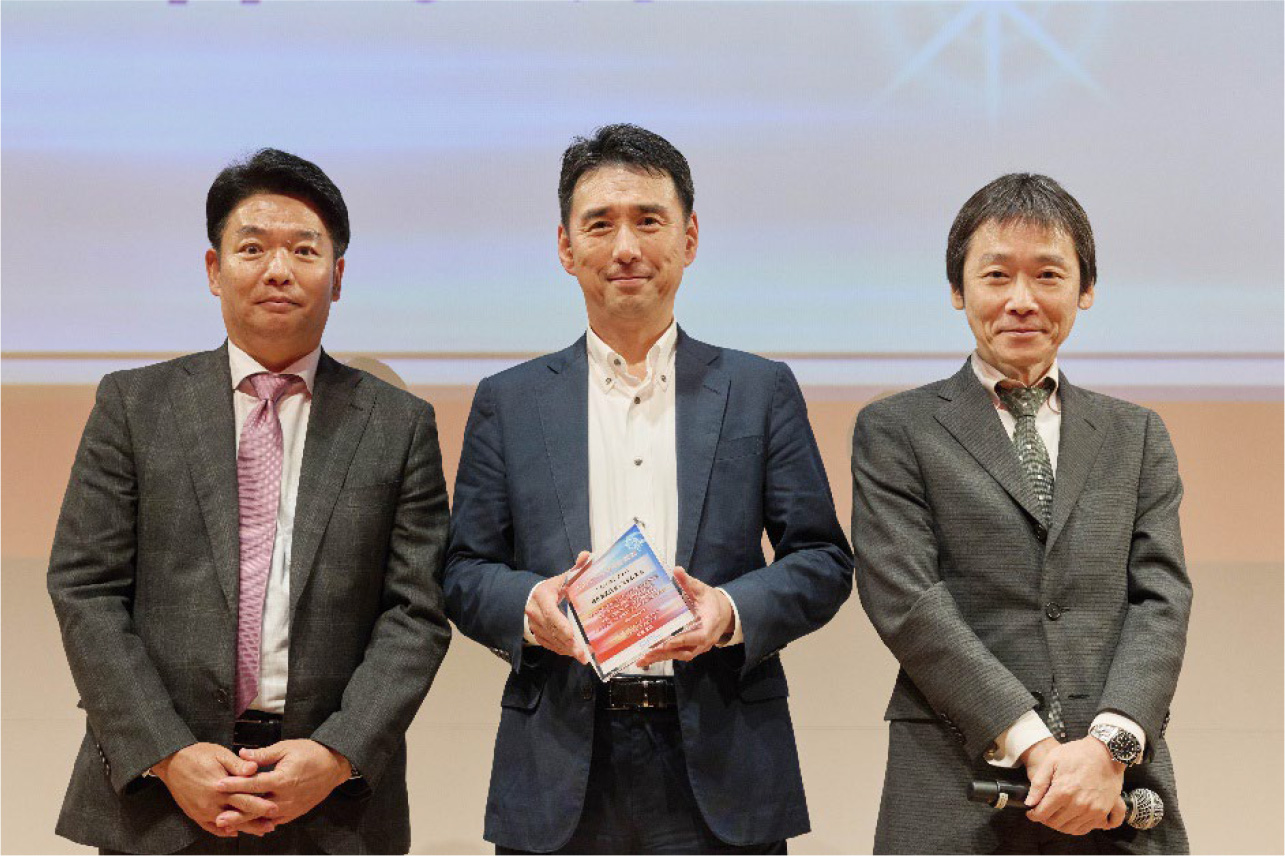 表彰式の様子。左から、DAL 代表取締役社長執行役員 安原 武志様、日立システムズ 取締役 常務執行役員 兼 産業・流通事業グループ長 長谷 正嗣、DAL 取締役執行役員営業本部長 下山 勝義様